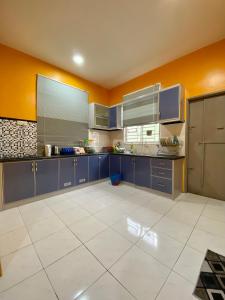 uma grande cozinha com armários azuis e paredes amarelas em DeSyafiq Homestay em Kuala Kedah