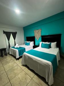 two beds in a room with blue walls at Hotel Tamtokow in Ciudad Valles