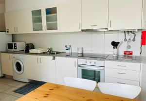 eine Küche mit weißen Schränken und einem Holztisch in der Unterkunft Apartamento da vila, Porto Santo. in Vila Baleira