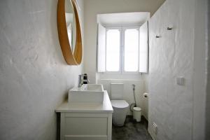 een badkamer met een wastafel, een toilet en een spiegel bij Casa Dona Ana in Tavira