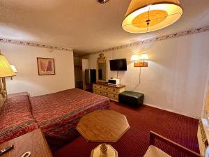 une chambre d'hôtel avec un lit et une table dans l'établissement Ambassy Motel, à Salina