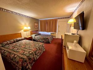 a hotel room with two beds and a flat screen tv at Ambassy Motel in Salina