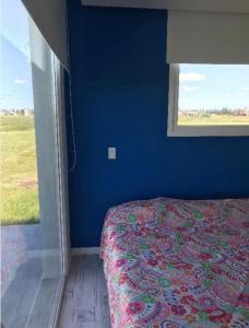 een slaapkamer met een bed met een blauwe muur en een raam bij Excelente Casa Country in Oliden