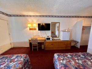 a hotel room with a desk and a bed and a mirror at Ambassy Motel in Salina