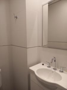 Baño blanco con lavabo y espejo en ALTOS DE STELLA MARIS Excelente Departamento y ubicación en Mar del Plata