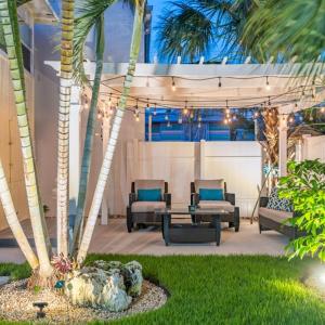 布雷登頓海灘的住宿－Lovely 2 bedrooms, steps away from the beach.，一个带椅子和桌子的庭院,并种植了棕榈树