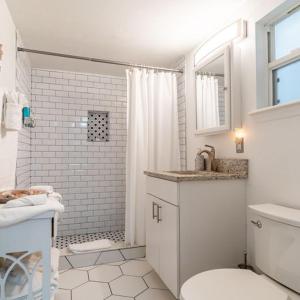 a white bathroom with a shower and a toilet at Lovely 2 bedrooms, steps away from the beach. in Bradenton Beach