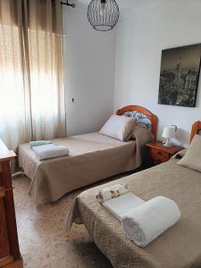 a bedroom with two beds and a chandelier at PISO EN 2* LINEA DE PLAYA in Barbate
