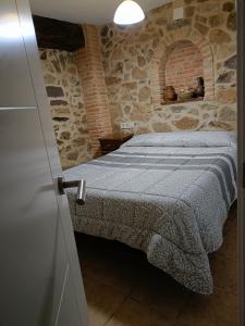 1 dormitorio con 1 cama en una pared de piedra en Casa Rural Roquemar, en Guijo de Granadilla