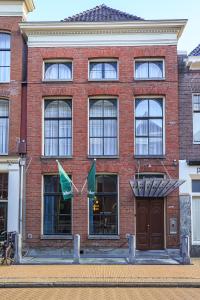 een bakstenen gebouw met twee vlaggen ervoor bij Hotel Halbert in Groningen