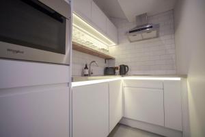 a white kitchen with a sink and a microwave at higgihaus Apartment 5 Clare Street Aparthotel Central Location in Bristol