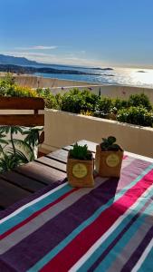 VUE MER EXCEPTIONNELLE - GRANDE TERRASSE et PISCINE في باندول: طاولة مع اثنين من النباتات الفخارية موضوعة على رأس الشاطئ