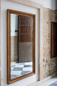 a mirror with a wooden frame on a wall at Hotel Tugasa Casa Palacio Medina Sidonia in Medina Sidonia