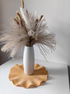 a white vase with dried flowers on a table at Adonis Apartment in Vienna