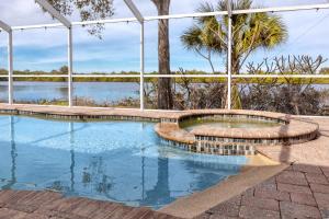 een zwembad met een patio en bomen op de achtergrond bij Blue Heron Lakeview Pool Home Close to Clearwater in Largo