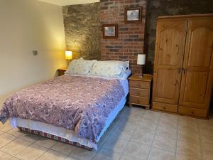1 dormitorio con cama y pared de ladrillo en The Slates Apartments - Fuchsia & Orchard Apartments en Irvinestown