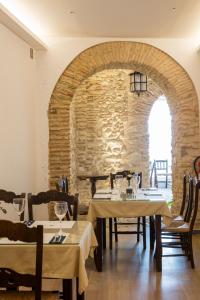 ein Esszimmer mit Tischen und einer Steinmauer in der Unterkunft Hotel Tugasa Casa Palacio Medina Sidonia in Medina-Sidonia