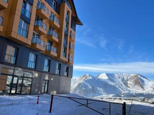 a hotel in the snow with mountains in the background at Delux apartment for 6 guest, new gudauri in Gudauri