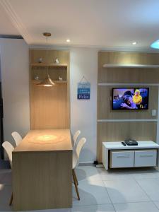 a room with a table and a tv on a wall at Apto novo pertinho da praia em Boracéia, Bertioga in Bertioga