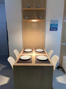 a wooden table with white chairs around it at Apto novo pertinho da praia em Boracéia, Bertioga in Bertioga