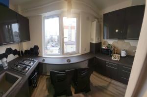 a kitchen with black cabinets and a window and a stove at Studio 28 Constantin Brancoveanu, Craiovita, self check-in in Craiova