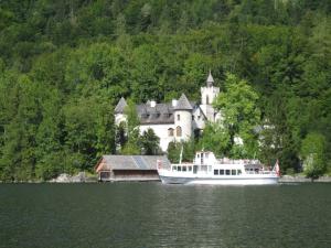 a boat in the water in front of a castle at Seehof Royer in Obertraun