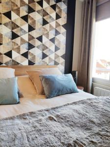 een slaapkamer met een bed met kussens en een muur bij Superbe apt cosy à 500m de la plage pour 4 pers in Fort-Mahon-Plage