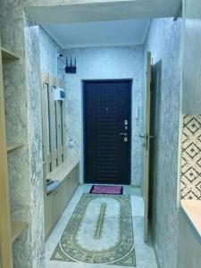 a hallway of a bathroom with a black door at Студия в ЖК Ушсункар in Almaty