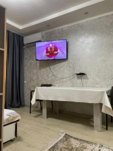 a living room with a table and a tv on a wall at Студия в ЖК Ушсункар in Almaty