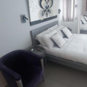 um quarto com uma cama branca e uma cadeira em studio by the sea em Ashdod