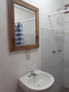 La salle de bains est pourvue d'un lavabo blanc et d'un miroir. dans l'établissement Andivi, à Arroyo Cruz