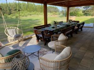 a patio with a table and chairs and a swing at Dom w lesie przy stawach in Dylewo