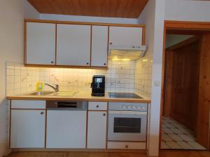 Appartements Winter Anita في فلاخاو: مطبخ مع دواليب بيضاء ومغسلة