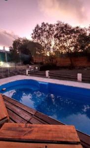 a swimming pool with a wooden deck and blue water at Cabaña con vista al Cerro Arco y la ciudad de Mendoza in Las Heras