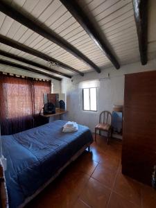 a bedroom with a blue bed and a chair at Cabaña con vista al Cerro Arco y la ciudad de Mendoza in Las Heras