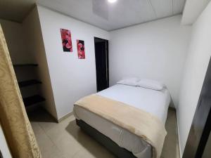 Habitación blanca con 1 cama con 2 cuadros en la pared en Casa Horeb, en Salento