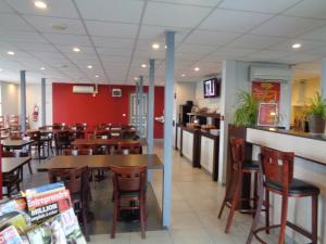 a restaurant with wooden tables and chairs and red walls at initial by balladins Roissy / Saint-Mard in Saint-Mard