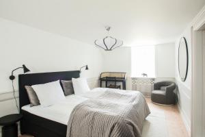 a white bedroom with a bed and a chair at Modern 3BR Duplex Flat in Nyhavn w Private Balcony in Copenhagen