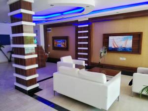 a lobby with white furniture and a column with a tv at Oba Suites Apartmani in Alanya