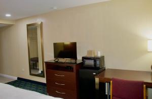 a hotel room with a television and a desk with a microwave at Royal Inn - North Augusta - Home Of The Masters - Augusta Downtown in Beech Island