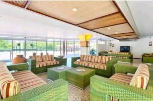 ein Wohnzimmer mit grünen Möbeln und vielen Fenstern in der Unterkunft Gran Lençóis Flat Residen in Barreirinhas
