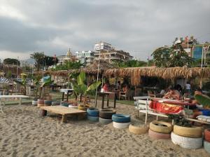 una spiaggia sabbiosa con tavoli, sedie e posti a sedere di Oba Suites Apartmani a Alanya
