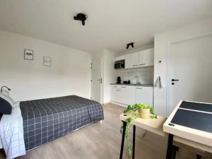 a white bedroom with a bed and a kitchen at City and Nature in Ghent