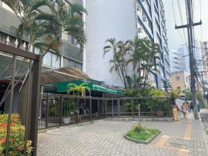 a building with a gate and palm trees in a city at Barra Apart Service in Salvador