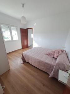 a white bedroom with a bed and a wooden floor at Casa das Laxas, recién reformada con 5 dormitorios en entorno natural in Porto do Son