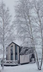 a building covered in snow next to two trees at Ptaszkova PrzyStań in Ptaszkowa