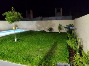 un patio trasero por la noche con piscina en Alquiler Temporario Capitan Bermudez en Ricardone