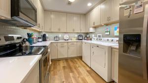a large kitchen with white cabinets and wooden floors at ISLAND ESCAPE home in Jekyll Island +11 photos
