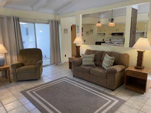 a living room with a couch and a chair at SEA COTTAGE APARTMENT Duplex in Jekyll Island