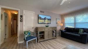 un soggiorno con un divano nero e una TV di GOLDEN DAYS DUPLEX Duplex a Jekyll Island